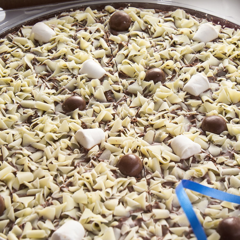 Honeycomb and Marshmallow Chocolate Pizza is topped with white chocolate curls, honeycombed rice balls and soft marshmallows